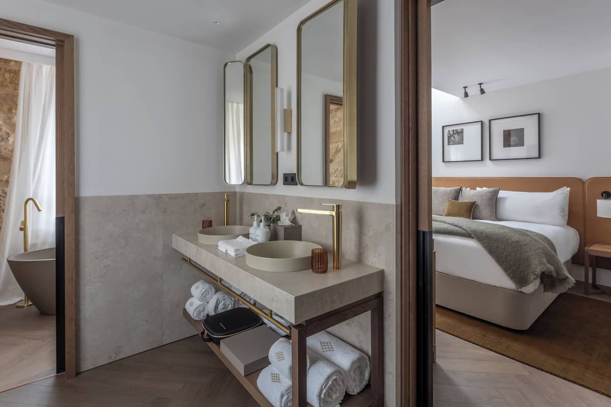 Un baño moderno con bañera, dos lavamanos y un mueble de tocador con toallas.