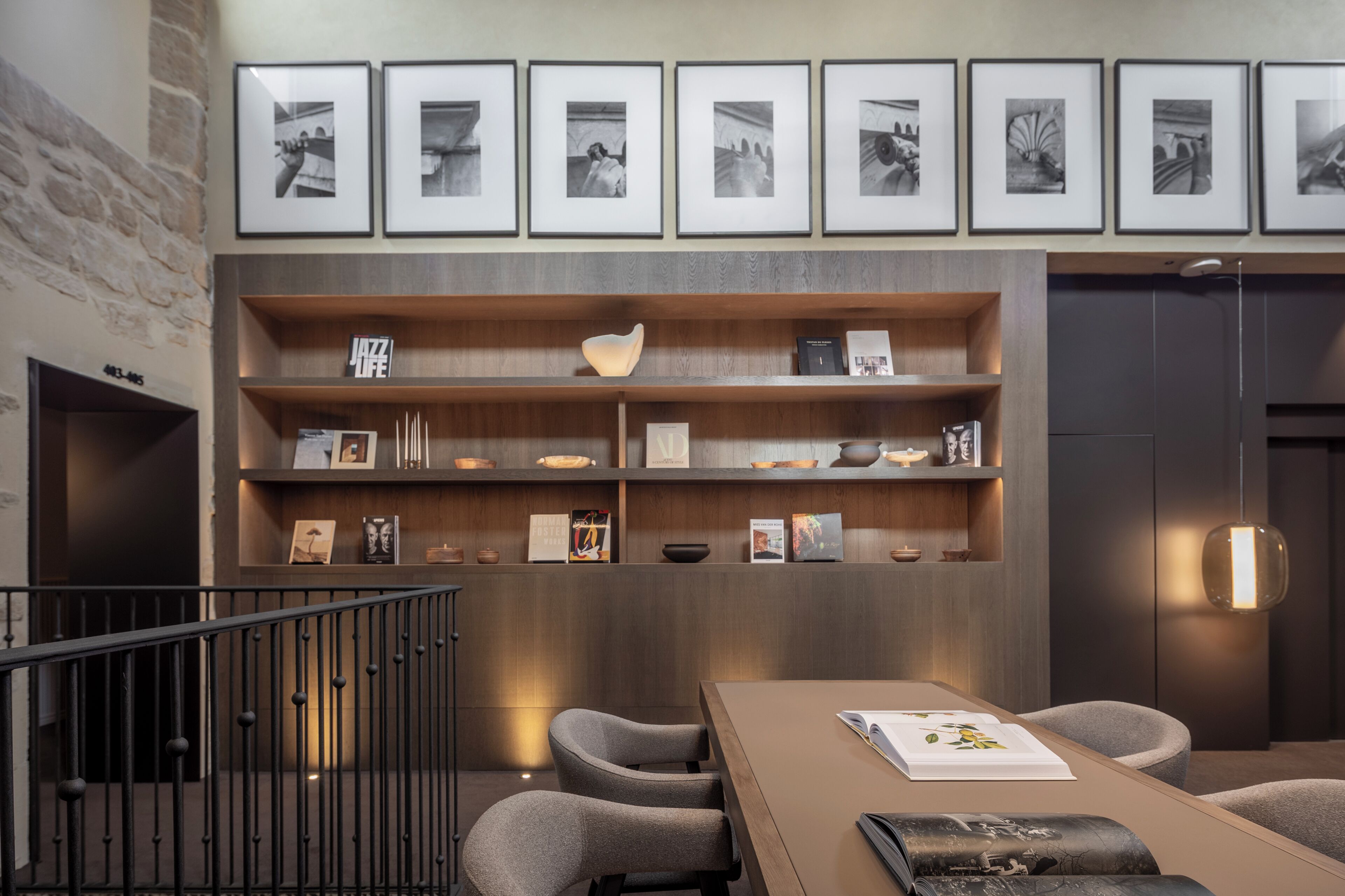 Un interior moderno con una estantería de madera, cuadros enmarcados y un comedor.