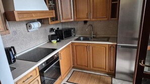 Una cocina moderna con armarios de madera, un refrigerador de acero inoxidable, un microondas y un horno empotrado.