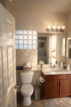 Ein Badezimmer mit Toilette, Waschbecken, Waschtisch und einem Fenster mit Milchglas.