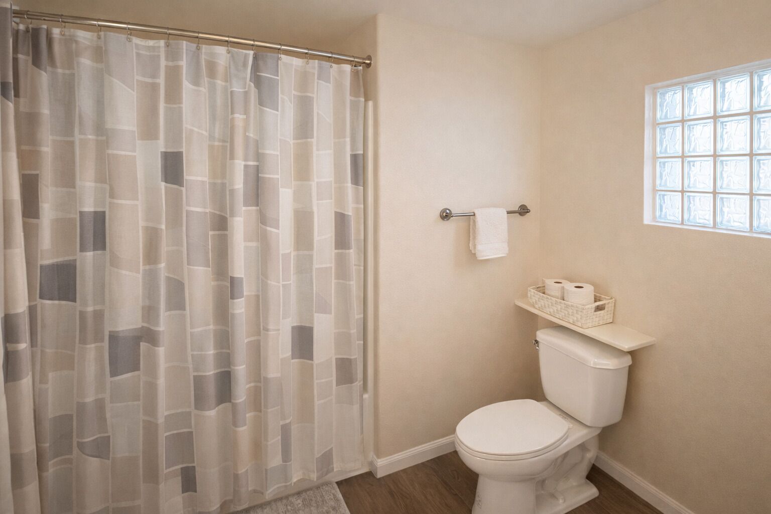 Une salle de bain avec un rideau de douche, des toilettes et une fenêtre.