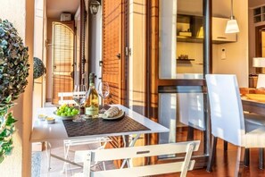 An outdoor dining area with a table set for two, a bottle of wine, and a basket of grapes. - Prada House: Modern Comfort with Terrace and Parking in Milan (Milano)