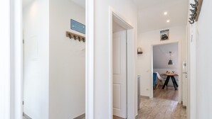 Un couloir avec un porte-manteau, une porte avec une pancarte et un coin repas avec une table et des chaises.