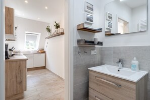 A modern kitchen with wooden cabinets, a built-in oven, and a window. - Ferienwohnung in St.peter Ording (St. Peter-Ording)