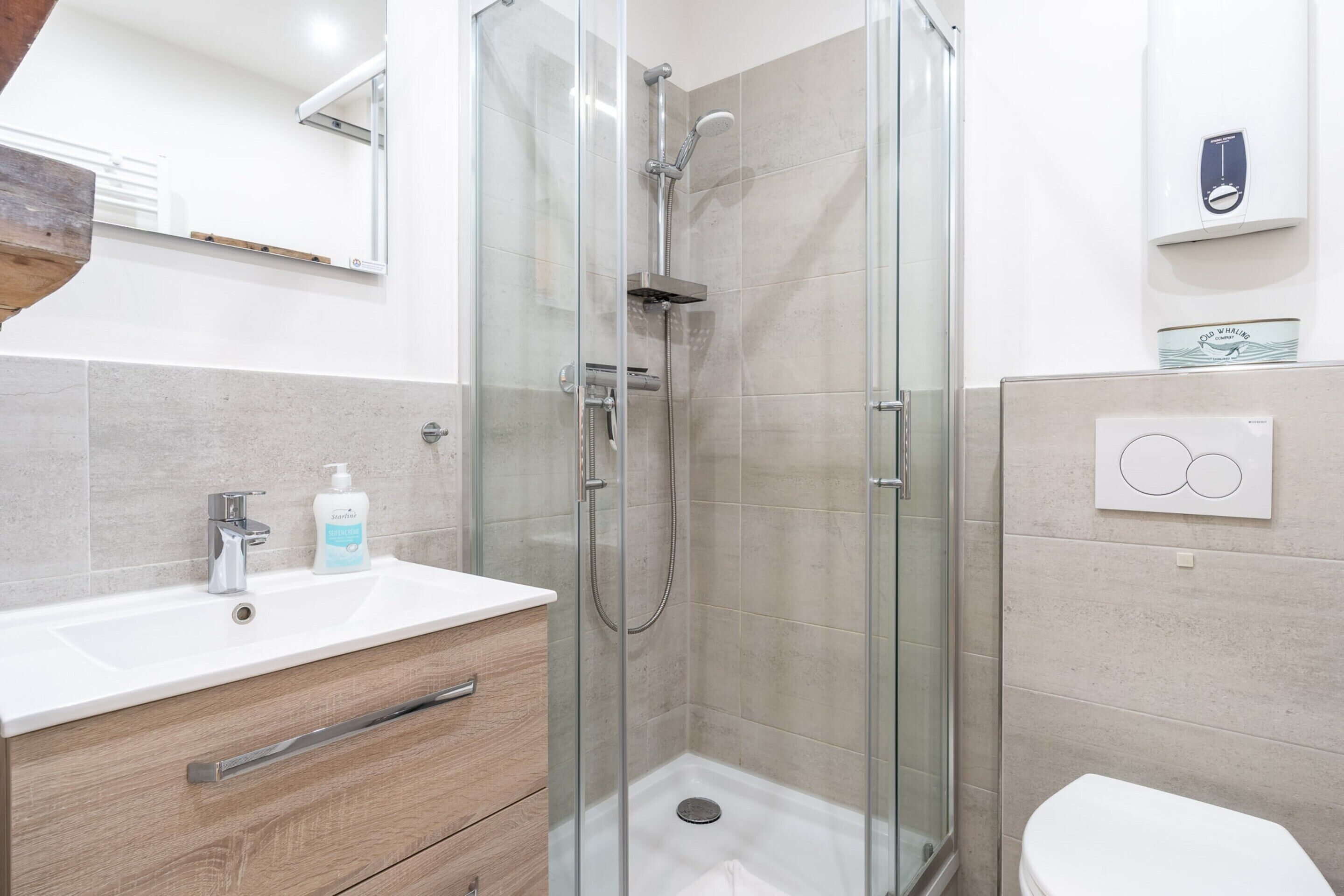 A modern bathroom with a glass-enclosed shower, a white sink, and a toilet.