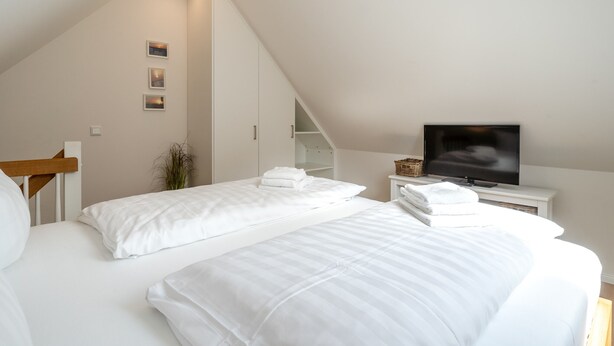 Une chambre avec deux lits, une télévision et un escalier menant à un étage supérieur.