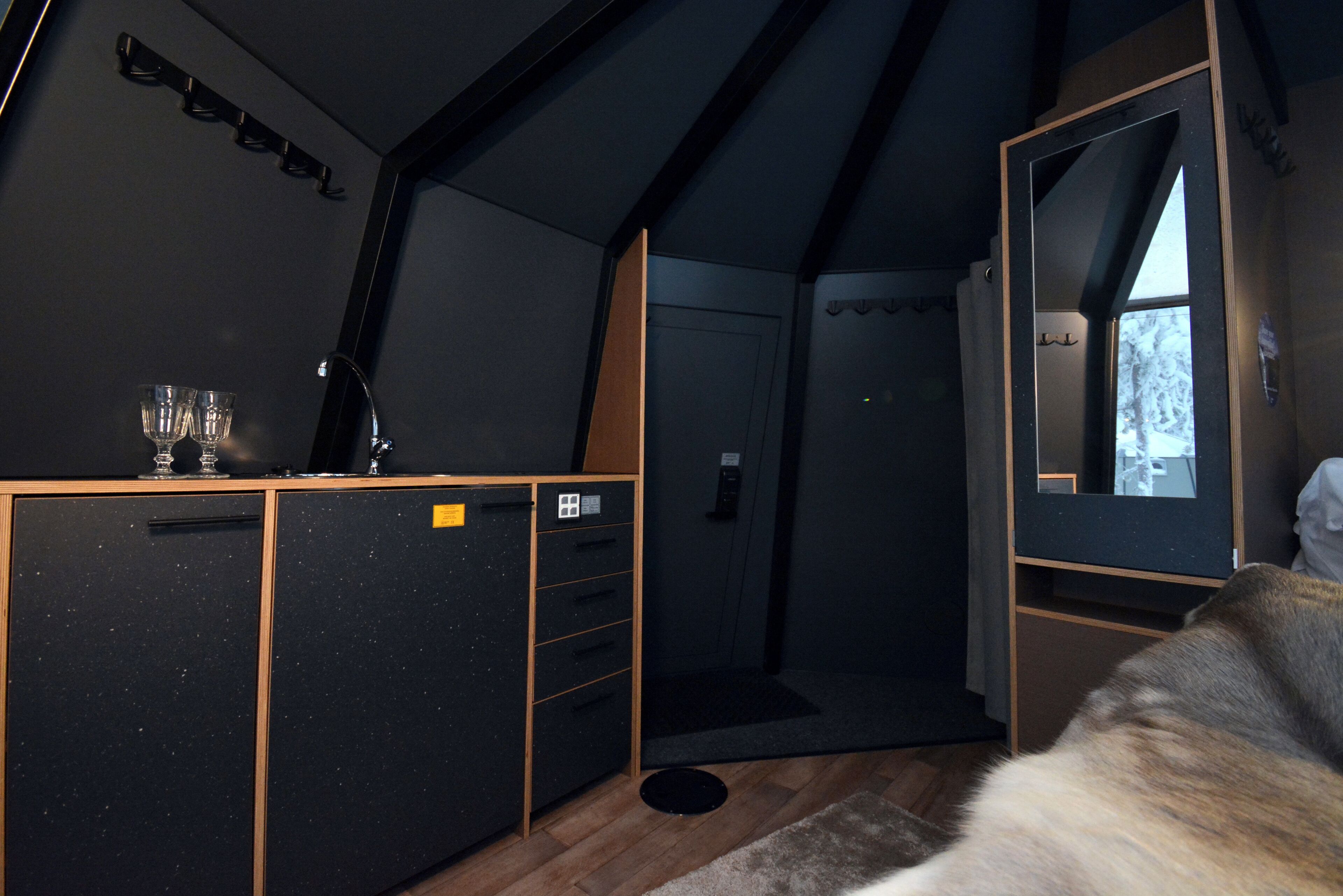 Une chambre moderne et compacte, dotée d’une kitchenette, d’un grand miroir et offrant une vue sur l’extérieur.