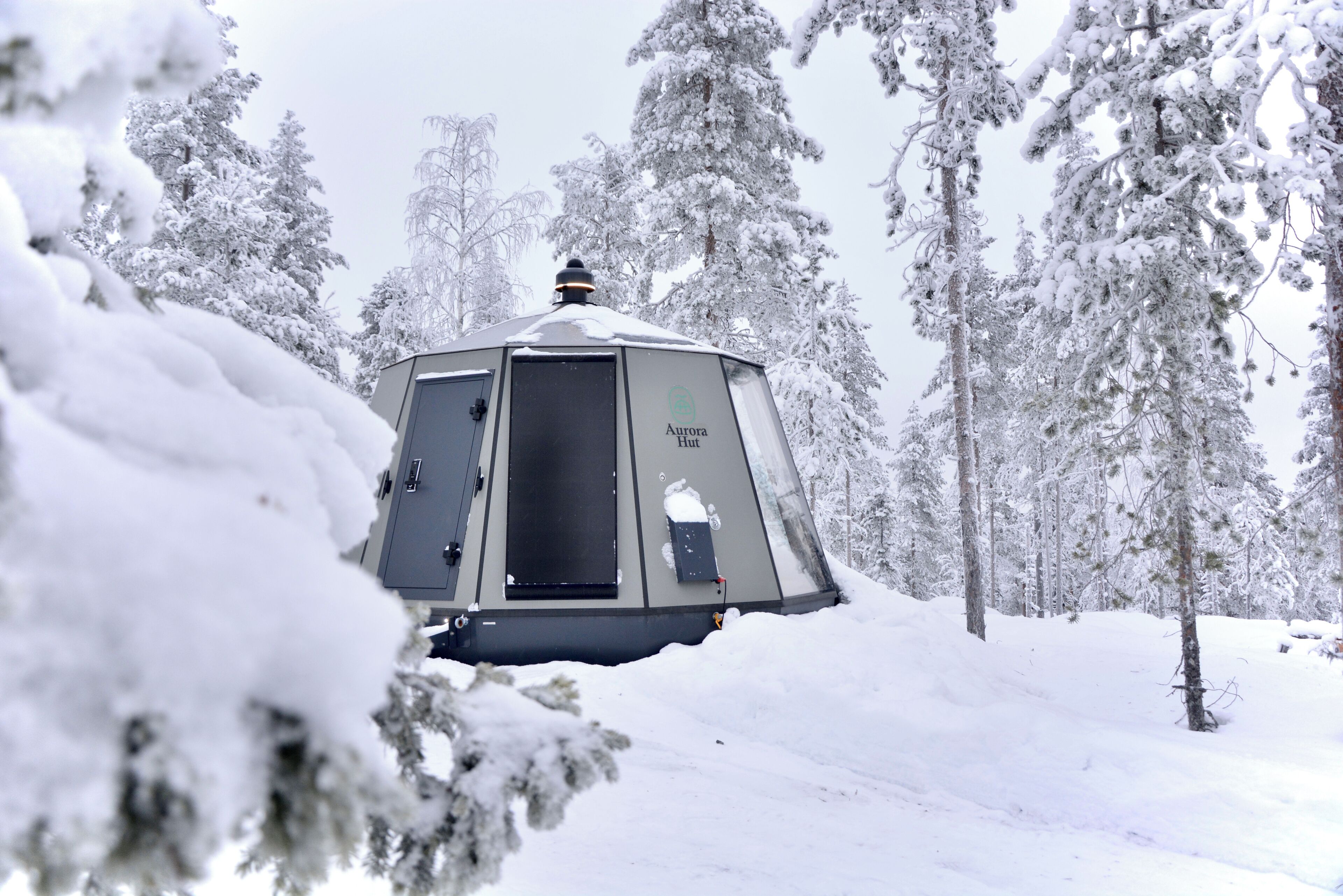 A snow-covered cabin with a sign reading "Aurora Hut."