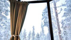 Ein Zimmer mit großem Fenster und Blick auf einen verschneiten Wald.