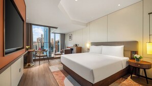 Ett modernt hotellrum med en stor säng, ett skrivbord och utsikt över stadsbilden.