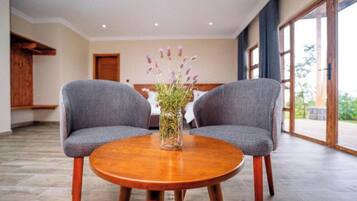 A room with two grey upholstered chairs facing a round wooden table with a vase of flowers.