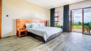 Une chambre à coucher avec une tête de lit en bois, un lit, une table de chevet et une vue sur l’extérieur grâce à une porte coulissante.