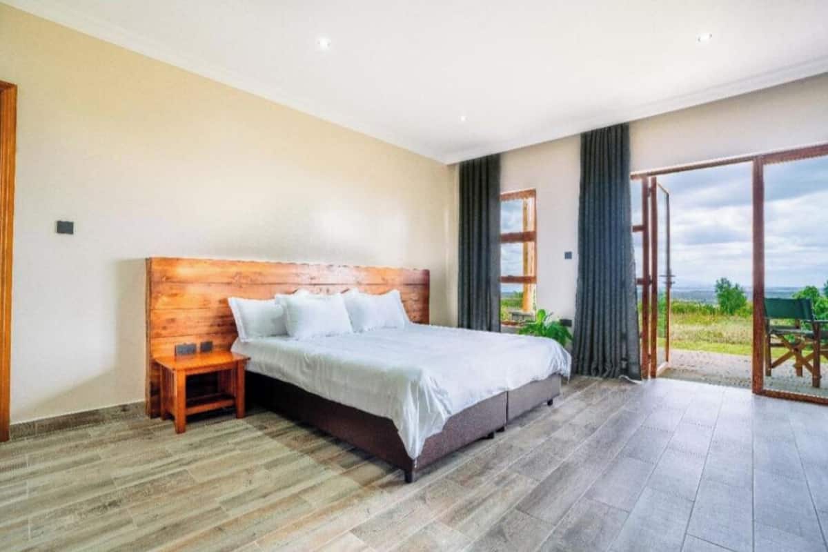 Une chambre à coucher avec une tête de lit en bois, un lit, une table de chevet et une vue sur l’extérieur grâce à une porte coulissante.