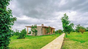 Une maison de plain-pied avec une façade en pierre, un porche en bois et un chemin pavé menant à l’entrée.