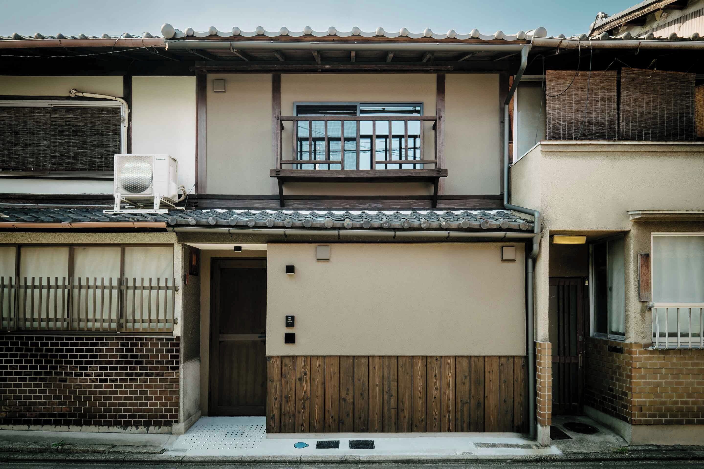 A traditional Japanese house with a wooden balcony, a sliding door, and a small air conditioning unit.