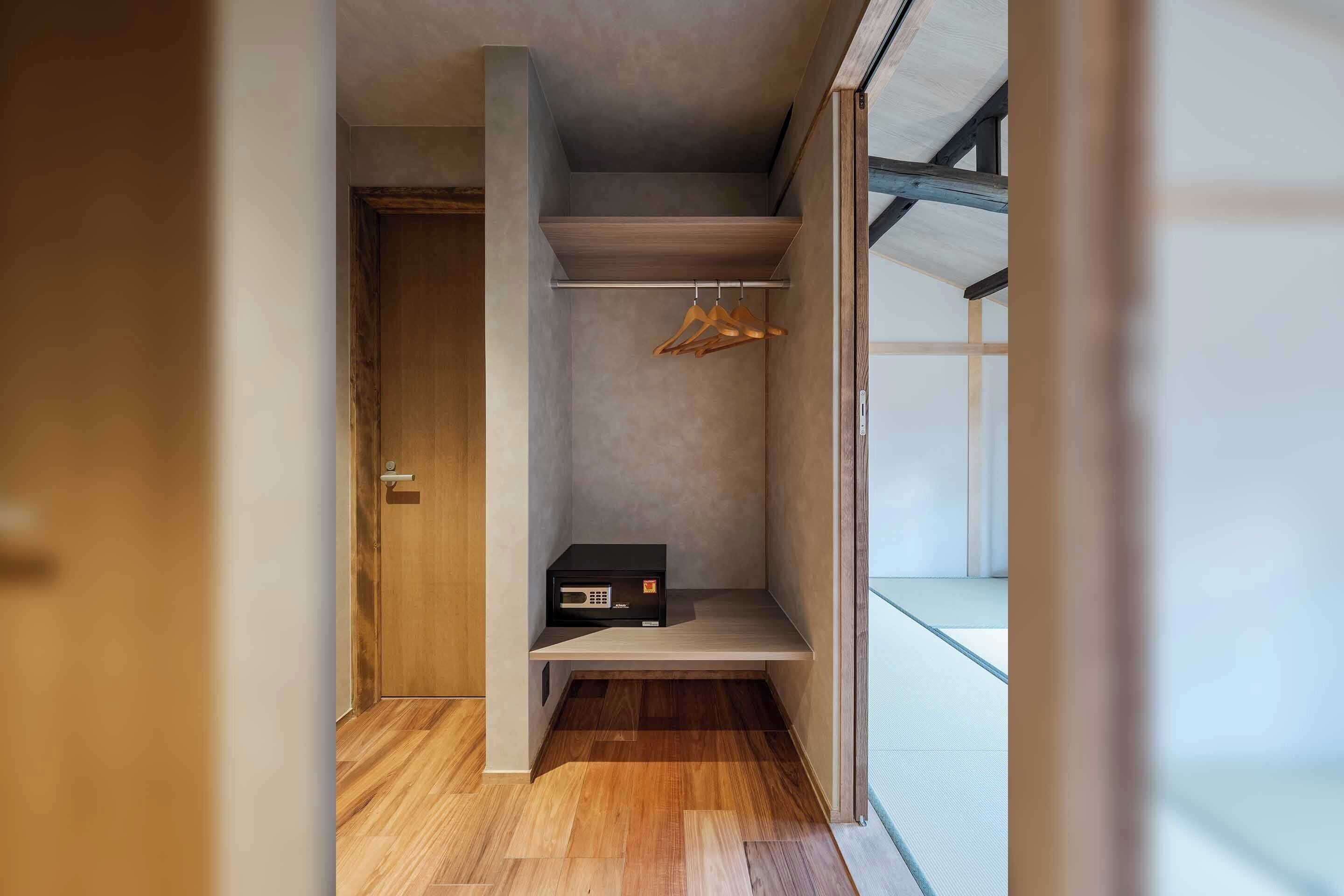 A compact room with a wooden floor, a built-in shelf, a microwave, and a hanging rack.