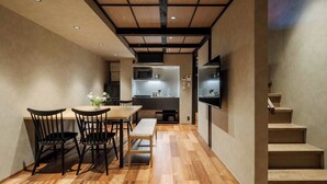Eine moderne Küche mit integrierten Geräten, ein Essbereich mit Holztisch und -stühlen sowie eine Treppe, die zu einer oberen Ebene führt.