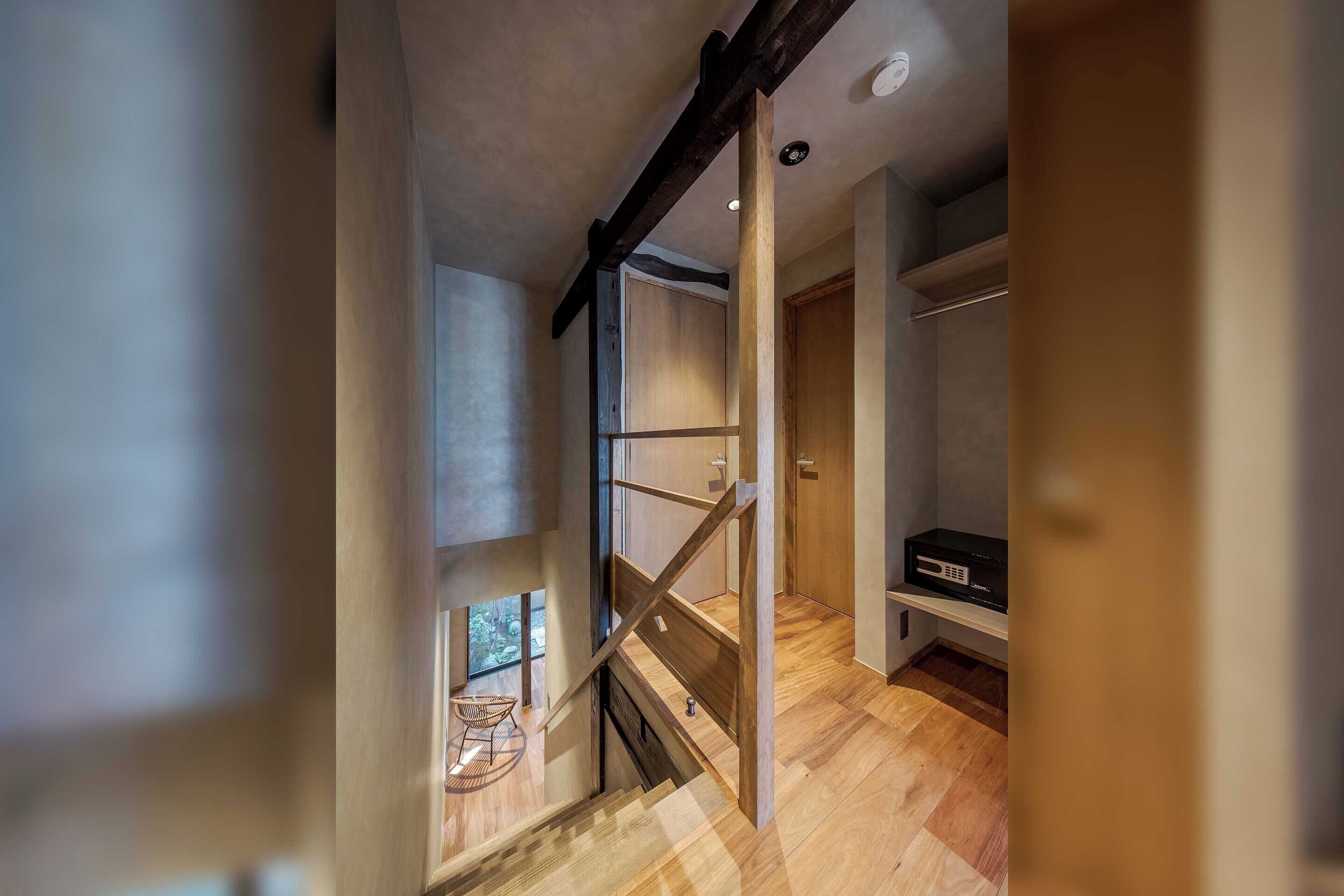 A modern interior with a wooden staircase, a small seating area, and a built-in entertainment unit.