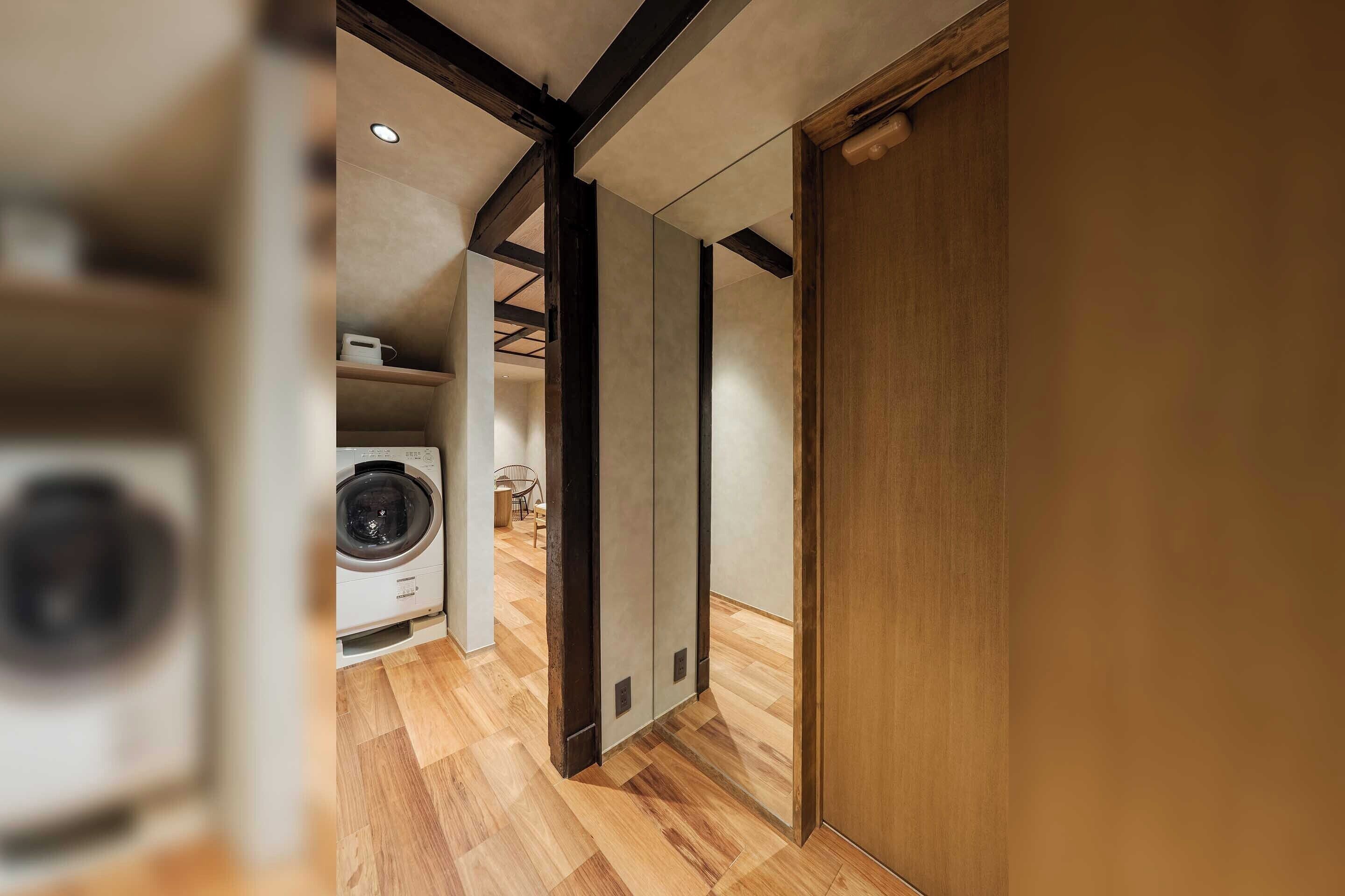 Un interior modern amb un terra de fusta, una màquina de rentar i una porta corredissa.