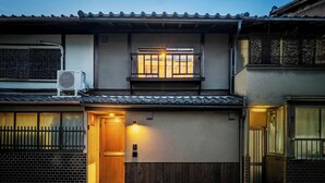 Ein traditionelles japanisches Haus mit Holztür, kleinem Balkon und Fenster mit Holzrahmen.