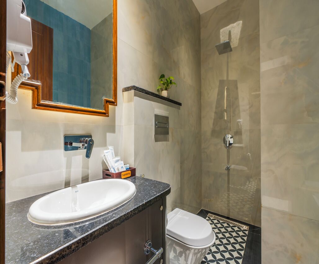 A bathroom with a sink, mirror, shower, and toilet.