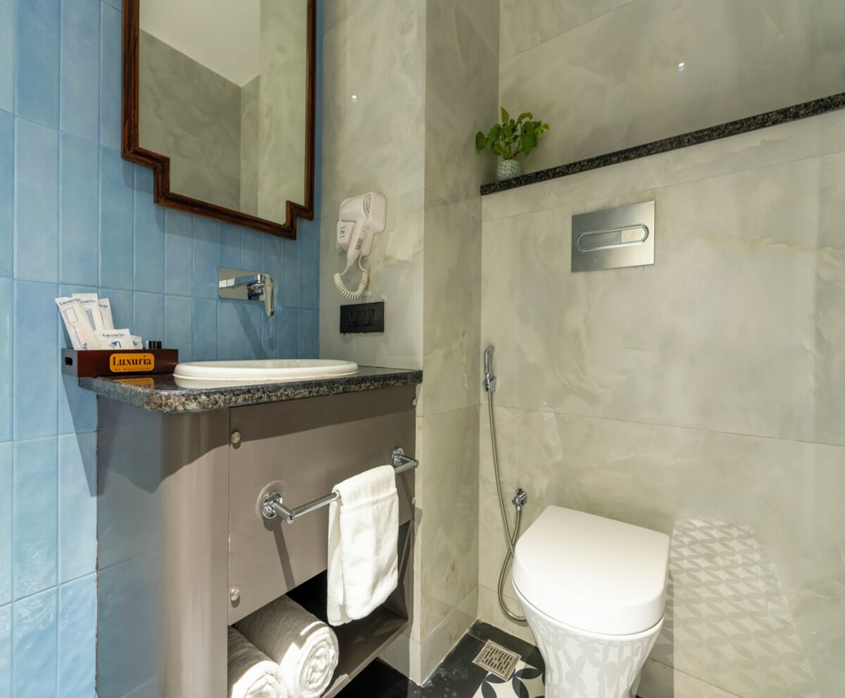 A modern bathroom with a marble sink, a hairdryer, a towel rack, and a toilet.