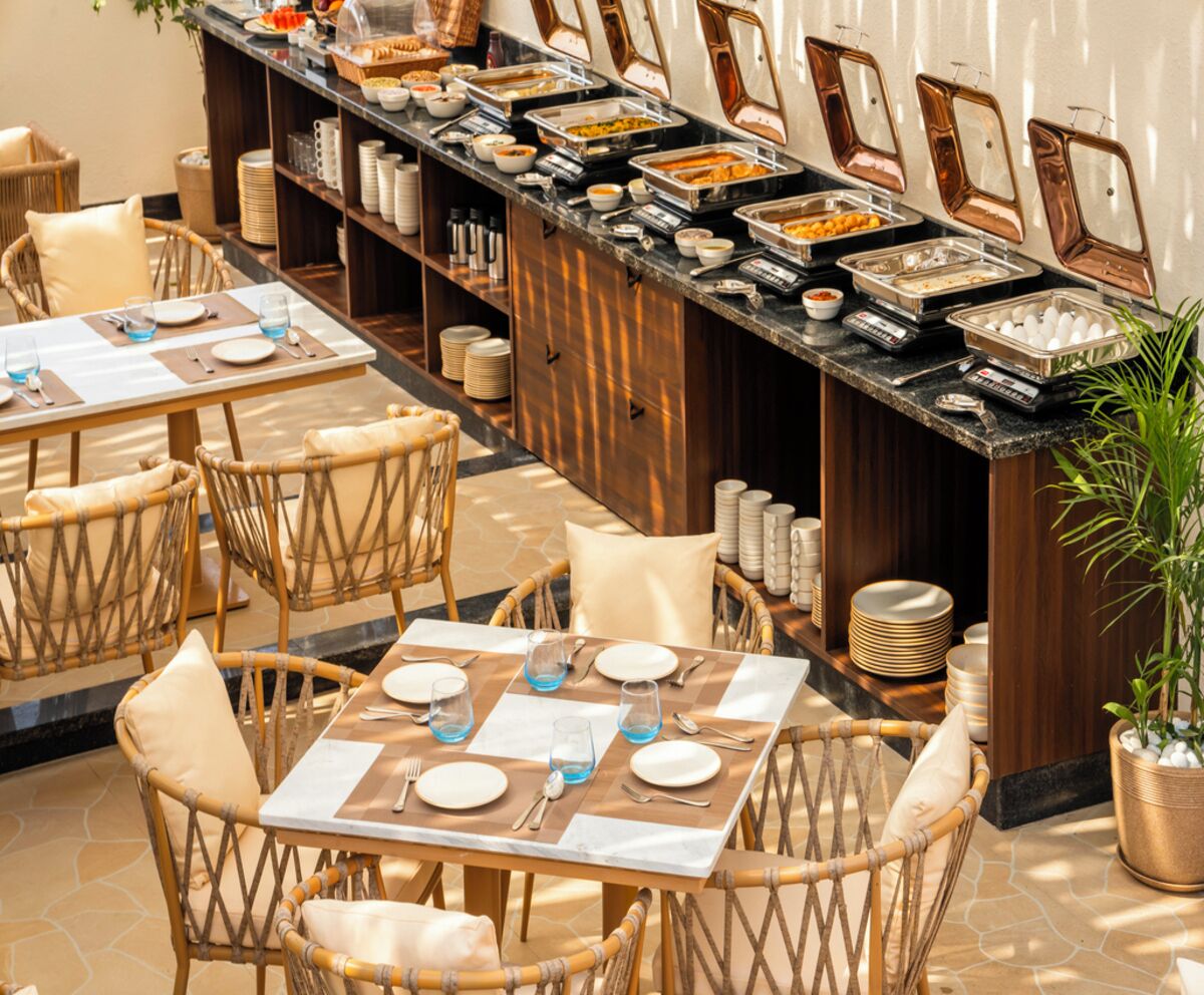 A buffet setup with multiple serving stations, wicker chairs, and a dining area with tables set for guests.