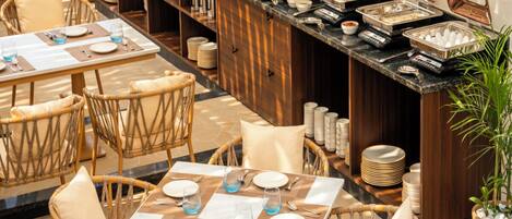 A buffet setup with multiple serving stations, wicker chairs, and a dining area with tables set for guests.