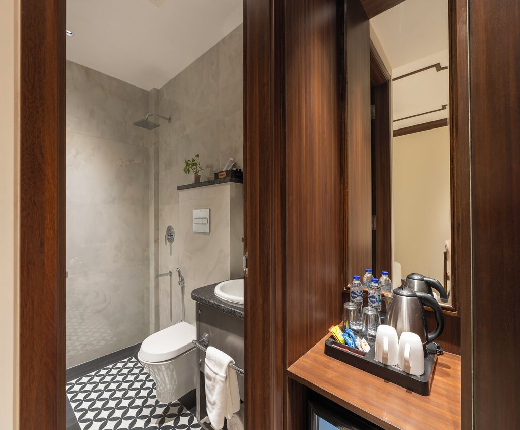 A modern bathroom with a shower, toilet, and sink. There is a tray with toiletries and a coffee maker on the counter.