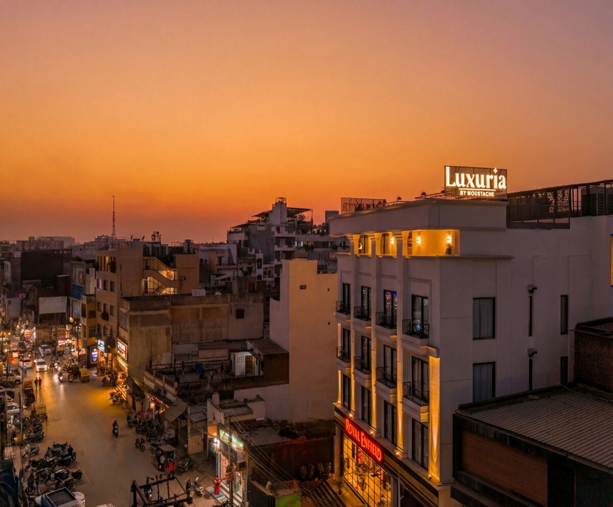 A cityscape at dusk with a prominent building labeled "Luxuria by Moustache" and a "Royal Field" sign.