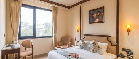 A hotel room with a large bed, two bedside tables, a desk, and a chair.