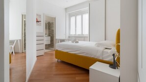 A modern bedroom with a bed, a desk, and a chair. - GuestHost - A modern and spacious 142 square meters apartment, perfect for five people, located on the second floor of a building with an elevator (NOT accessible to guests with disabilities).The property is just steps from the S. Agostino metro station, (Milan)