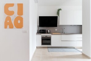 A modern kitchen with white cabinets, a flat-screen TV, a coffee maker, and a small oven. - GuestHost - A modern and spacious 142 square meters apartment, perfect for five people, located on the second floor of a building with an elevator (NOT accessible to guests with disabilities).The property is just steps from the S. Agostino metro station, (Milan)