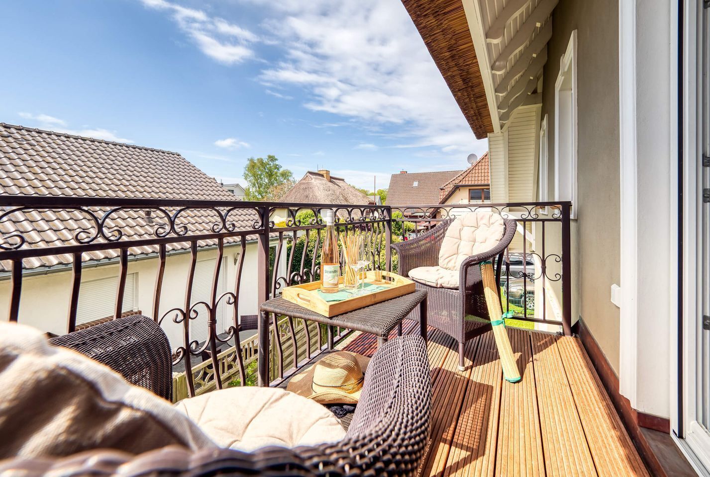 Ein Balkon mit Korbmöbeln, einem Tisch und einer Weinflasche.