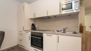 A modern kitchen with a built-in oven, microwave, and stainless steel sink. - Vacation apartment Meeresrauschen (Norden)