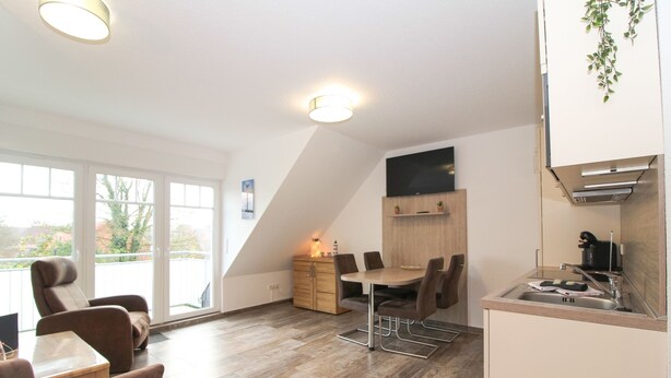 A modern kitchen with a dining area, large windows, and a view of the outdoors. - Vacation apartment Meeresrauschen (Norden)