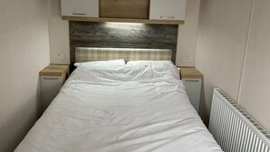 Un dormitorio compacto con una cama individual, cabecera de madera y dos mesitas de noche.