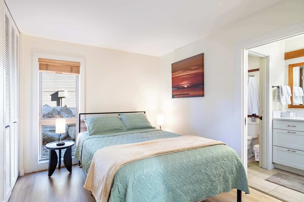 A bedroom with a bed, bedside table, lamp, and a painting on the wall.
