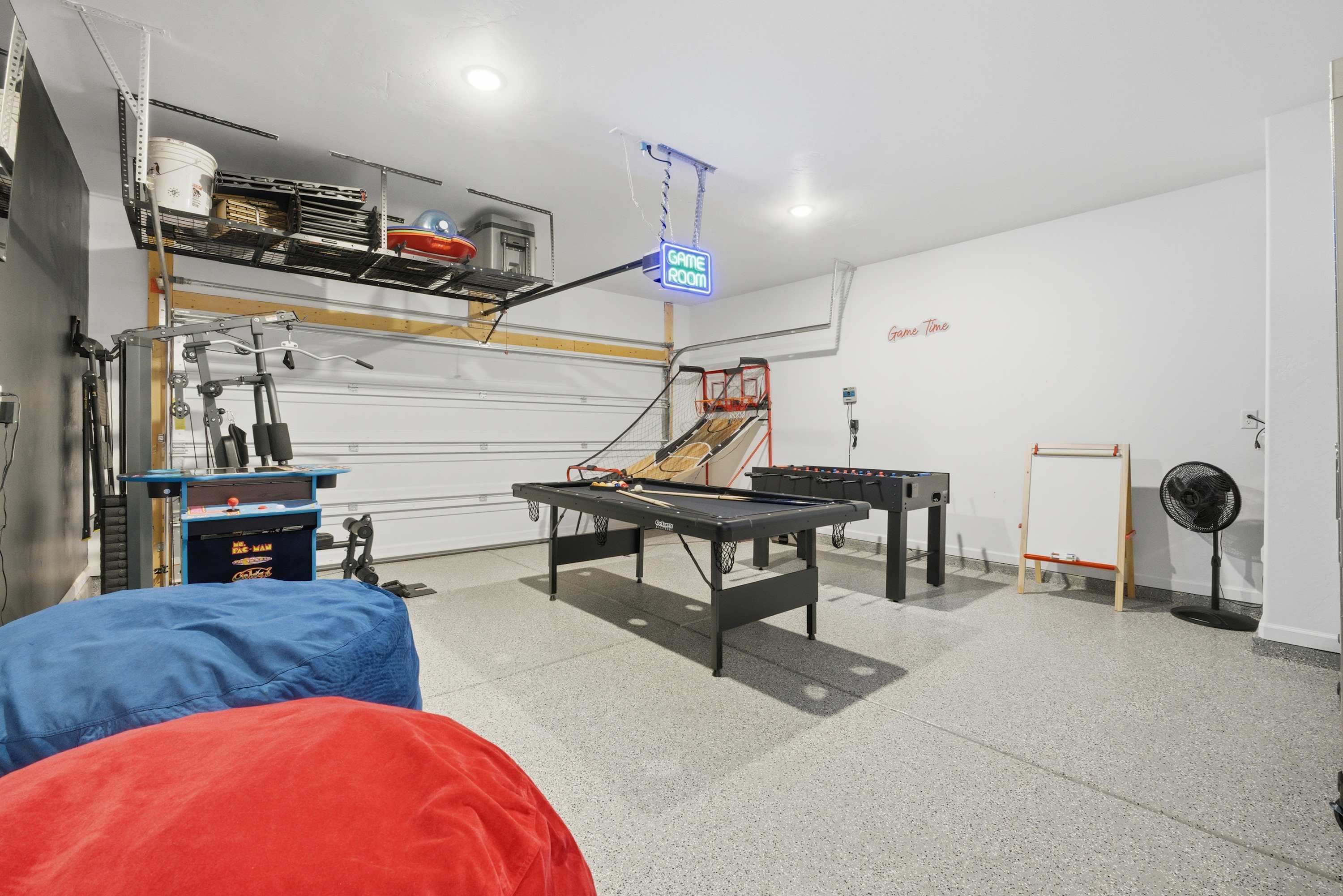 A game room with a pool table, exercise equipment, and a fan.