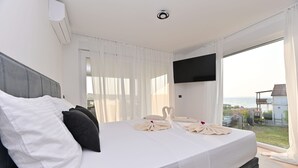 Ein Hotelzimmer mit Bett, Flachbildfernseher und Meerblick.