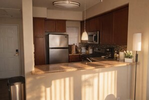 A modern kitchen with granite countertops, stainless steel appliances, and wooden cabinets. - Marina & Venice Beach Getaway (Marina del Rey)
