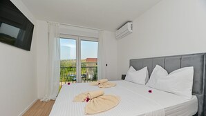 A hotel room with a large bed, white linens, a grey headboard, and a balcony with a view. - Villa Giovanni Zadar Villas (Razanac)