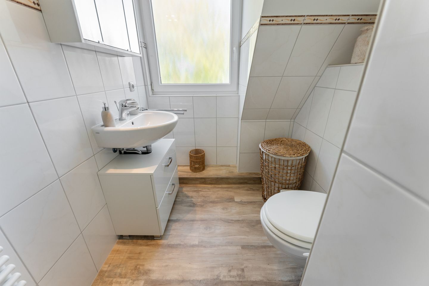 A compact bathroom with a sink, toilet, and a small window.