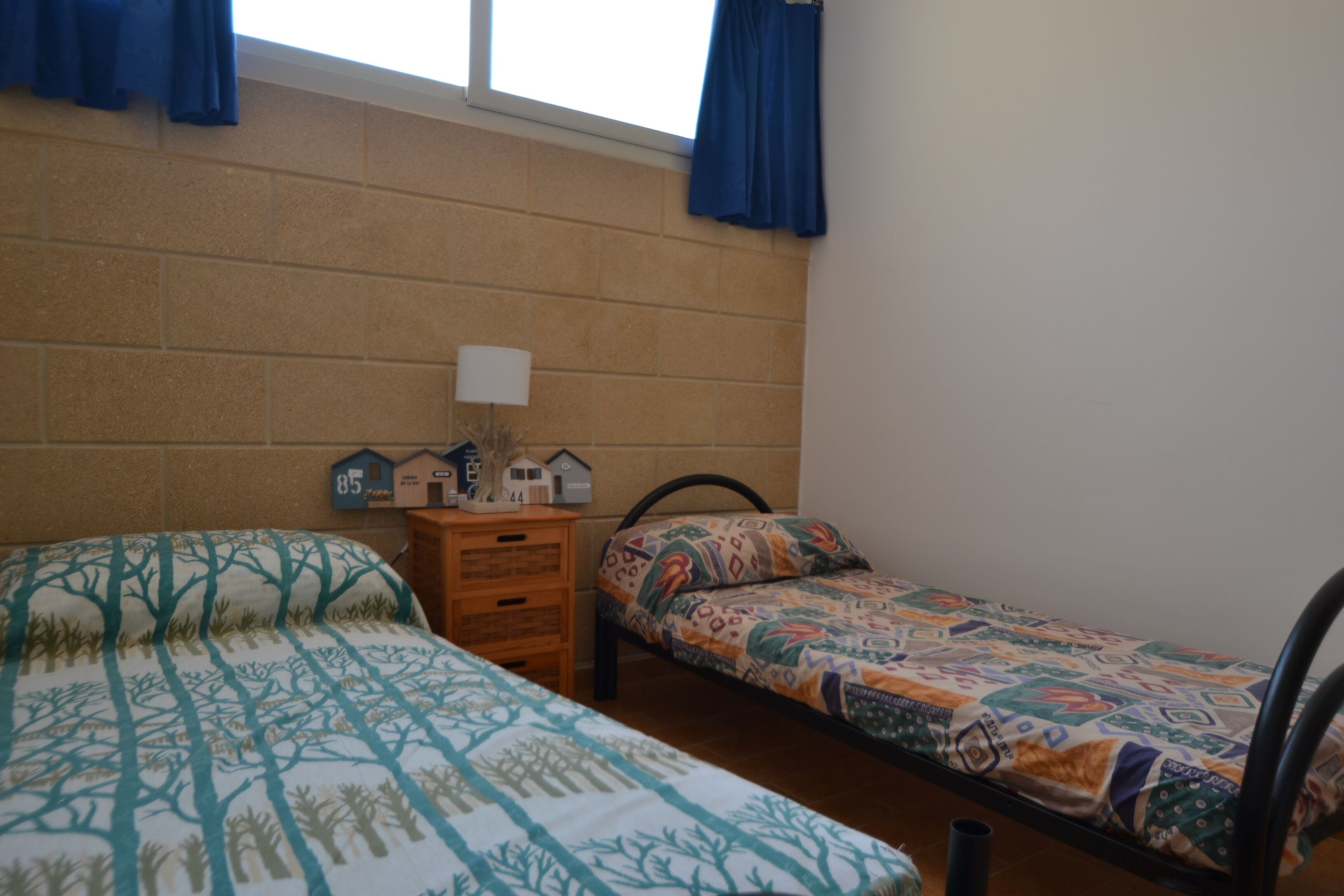 Una habitación tipo dormitorio con dos camas, un aparador y una lámpara.