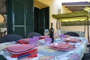 A table set for dining with pink plates, purple glasses, and a bottle of wine.