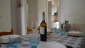 Ett matbord dukat med en vinflaska, glas, tallrikar och skålar.