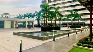 A modern outdoor area with a water feature, palm trees, and a building with multiple floors. - EXCLUSIVE APARTMENT IN PUERTO SANTA ANA |TOURISM AND TELEWORKING |WIFI + PARKING (Guayaquil)