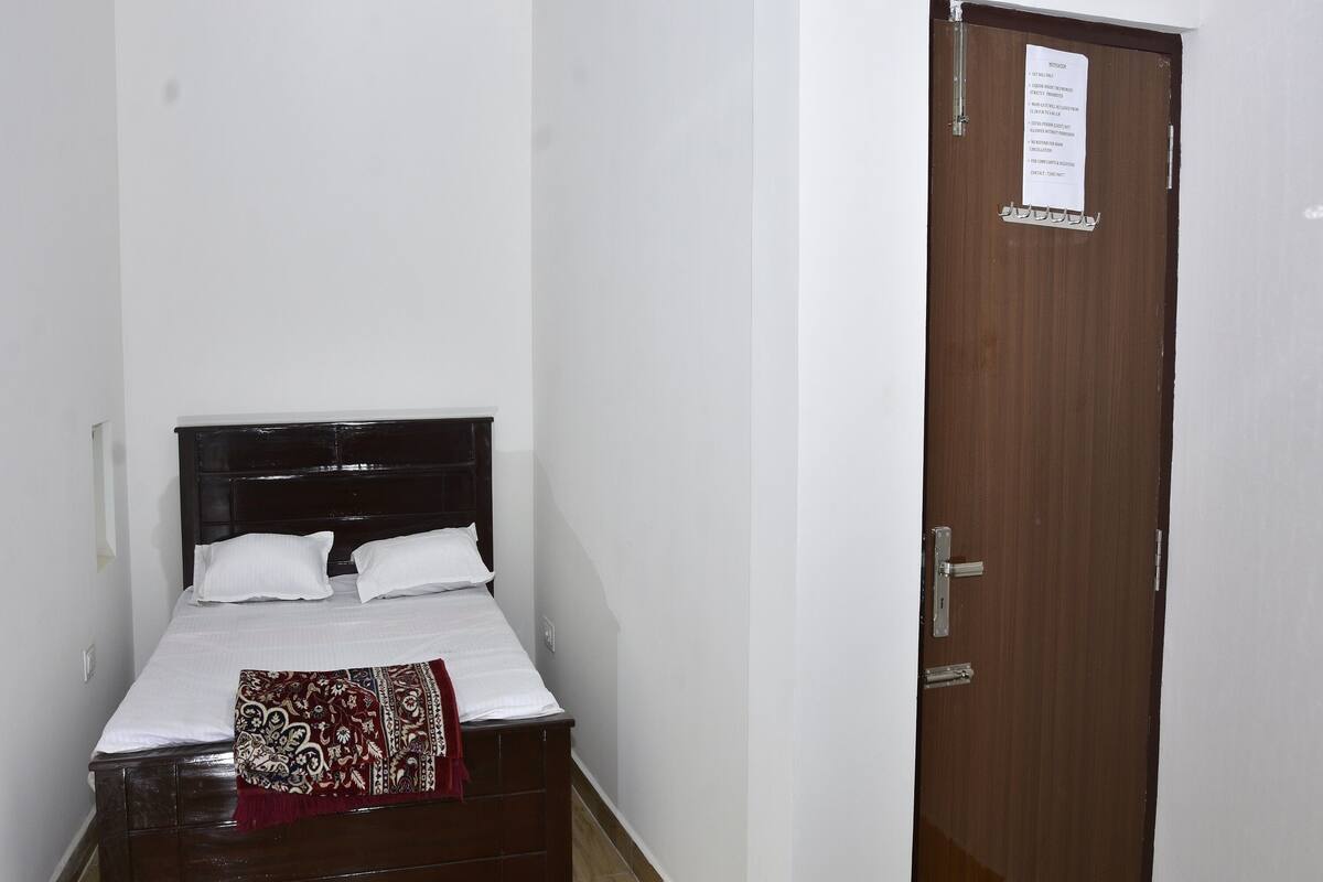 A bedroom with a bed, a ceiling fan, and a door with a notice.