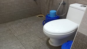 A bathroom with a toilet, a shower, and a blue water tank.