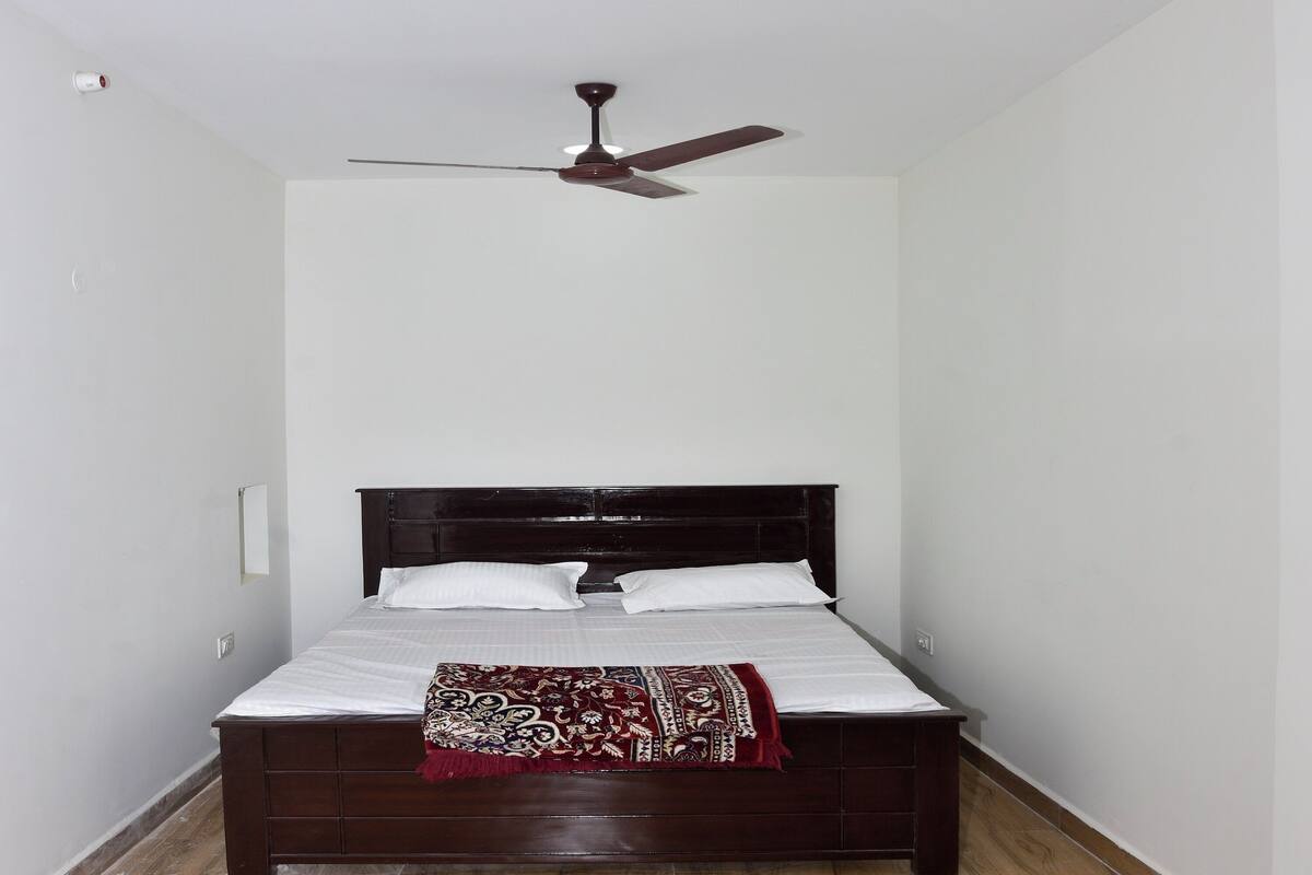 A bedroom with a bed, a ceiling fan, and a light fixture.